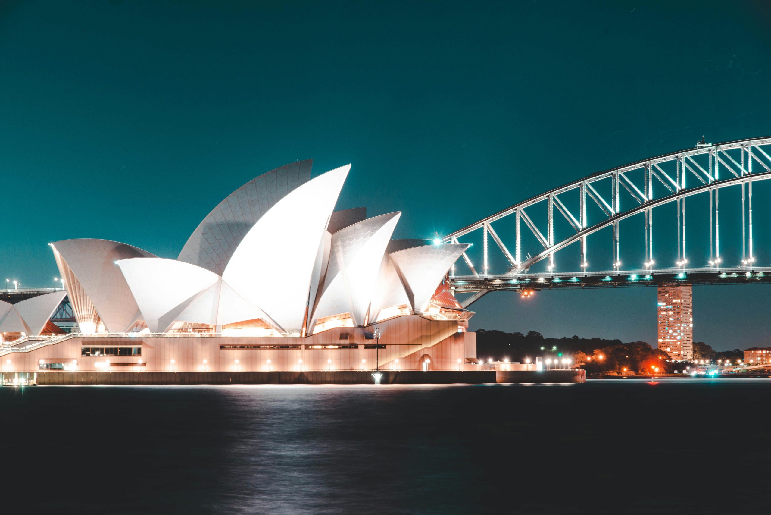 A Step-by-Step Guide to Immigrate to Australia from Dubai Stunning night view of Sydney Opera House and Harbour Bridge, beautifully illuminated against a clear sky.